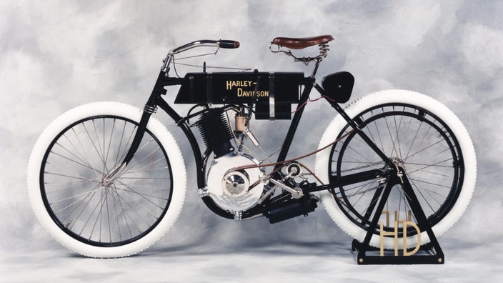 Ein schwarzes Fahrrad mit einem Ein-Zylinder-Motor, der mit dem Hinterreifen über einen Riemen verbunden ist | Bildquelle: Harley-Davidson Ein schwarzes Fahrrad mit einem Ein-Zylinder-Motor, der mit dem Hinterreifen über einen Riemen verbunden ist