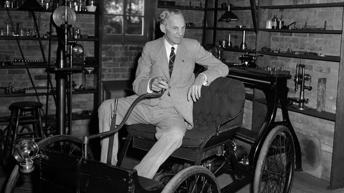 Henry Ford auf einem Modell seines ersten Autos