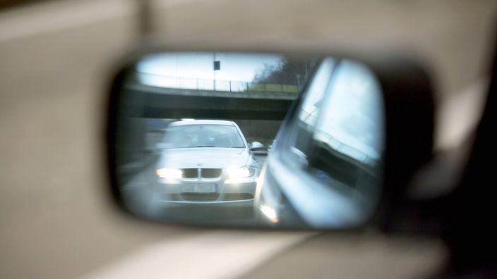 Blick in Rückspiegel auf der Autobahn. Ein Auto fährt auf wenige Meter auf