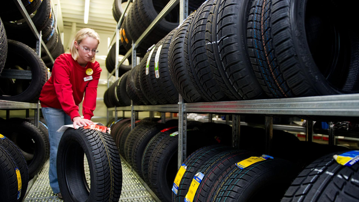 Eine Frau betrachtet einen Reifen in einem Reifenlager.