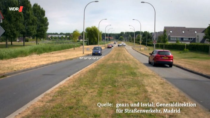 Eine Straße auf dem Land in den Niederlanden, in der Mitte ist ein breiter Grünstreifen, in die Fahrbahnen sind Hubbel integriert