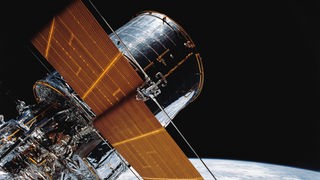 Das Foto zeigt Teile des riesigen Hubble-Weltraumteleskops. Im Hintergrund sind das All und die Erde zu sehen.