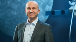 Pressefoto von Dr. Holger Krag. Im Hintergrund erkennt man einen Planeten und Teile einer Sonde.