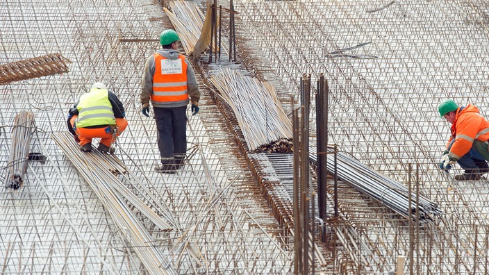 Bauarbeiter beim Flechten von Eisenmatten | Bildquelle: Dpa/Christoph Schmidt Bauarbeiter beim Flechten von Eisenmatten