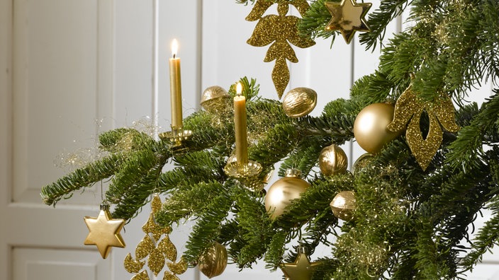 Goldenes Engelshaar liegt auf einem Zweig an einem Tannenbaum.