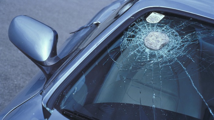 Ein etwa faustgroßer Stein in der Frontscheibe eiens Autos. Die Scheibe ist lediglich angerissen.