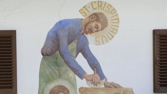 Wandmalerei: Sankt Crispinus, der Schutzpatron der Gerber, in zwei Szenen: Leder vernähend sowie gerbend.