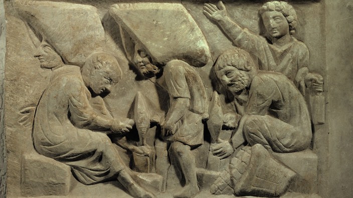 Ein Relief auf einem alten Grabstein zeigt, wie Arbeiter Marmor behauen und abtransportieren