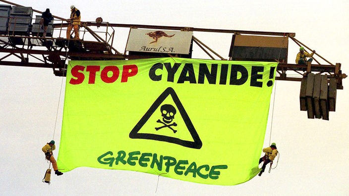 Greenpeaceaktivisten hängen ein Plakat mit der Aufschrift "Stoppt Cyanid" an einen Kranausleger.
