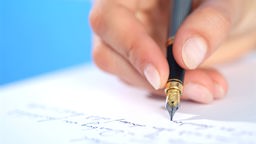 Frauenhand mit Füller schreibt einen Brief