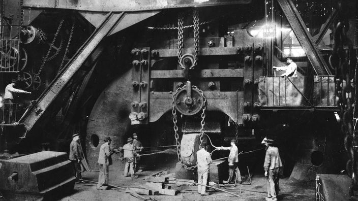 Historische Aufnahme des Schmiedehammers 'Fritz', den Krupp seit 1861 einsetzte. Zu sehen ist der Hammer und viele Arbeiter, die ihn bedienen.