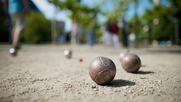 Boule-Kugeln aus Stahl liegen im Sand.
