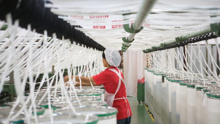 Baumwollfasern werden in einer Baumwollmühle zu Garn gesponnen