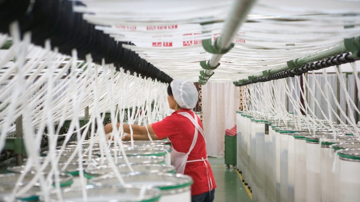 Baumwollfasern werden in einer Baumwollmühle zu Garn gesponnen | Bildquelle: dpa Picture-Alliance / James Hardy Baumwollfasern werden in einer Baumwollmühle zu Garn gesponnen