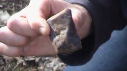 Thomas Grau hält einen Meteoriten in der Hand.