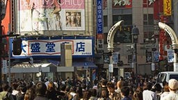 Bunte Werbeplakte und viele Menschen in einer Einkaufsstraße von Tokio.