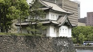 Das Foto zeigt einen Wachturm an der Außenmauer des Palastes, im Hintergrund als Kontrast das moderne Tokio.