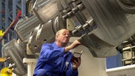 Ein Arbeiter kontrolliert einen Dieselmotor, der in einem Zulieferunternehmen in Rostock gefertigt wurde.