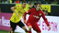 Lars Bender in rot-schwarzem Trikot von Bayer 04 Leverkusen und sein Zwillingsbruder Sven Bender im gelben Dress von Borussia Dortmund bei einem Bundesligaspiel Anfang 2013