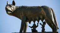 Kapitolinische Wölfin: Lebensgroße Figur einer Wölfin aus Bronze. Zwei Jungen-Figuren trinken an zwei ihrer Zitzen.